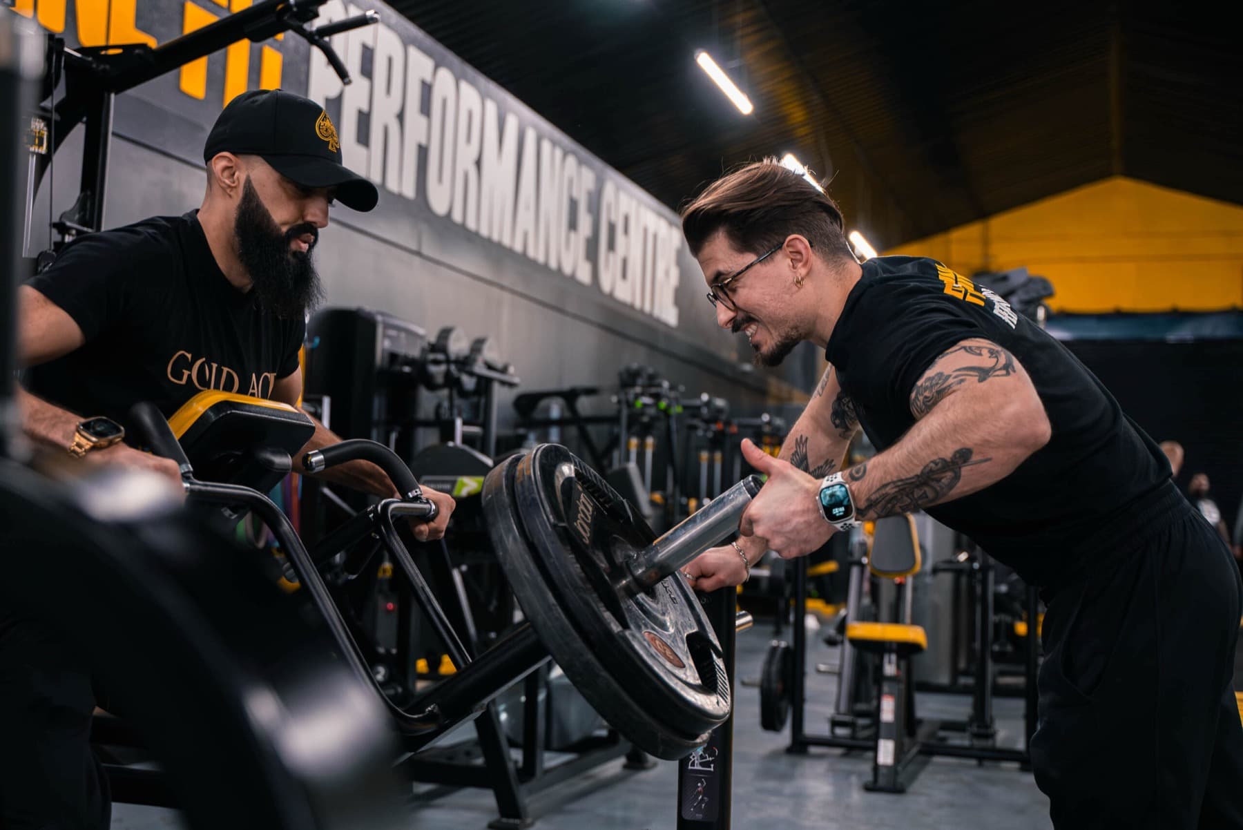 Two FLF coaches loading a plate on the gym floor